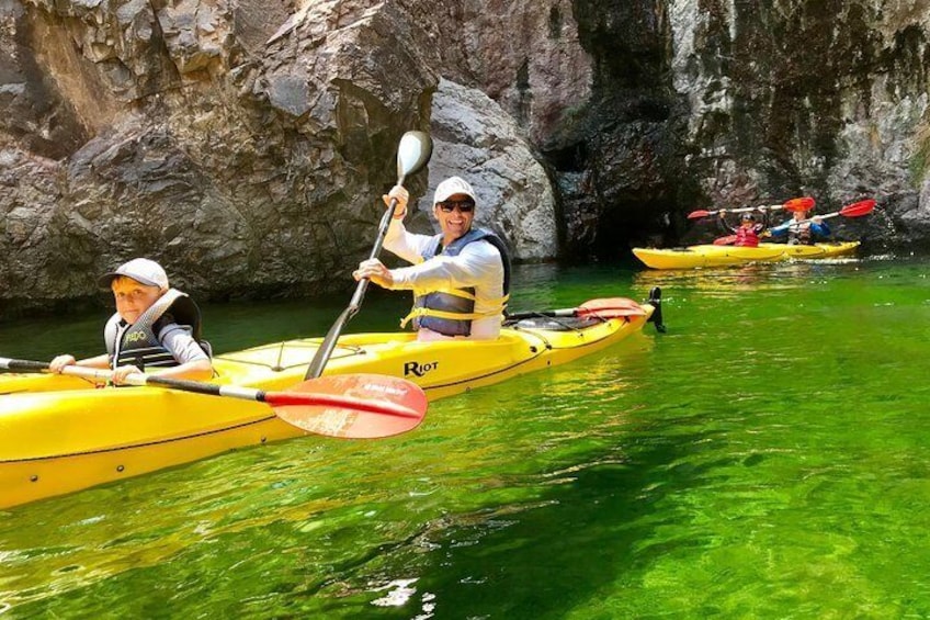 Two people kayaking in a yellow kayak with a rocky background. 5