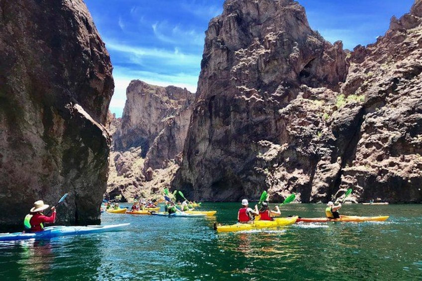 Kayakers navigating through a canyon with rocky cliffs. 3