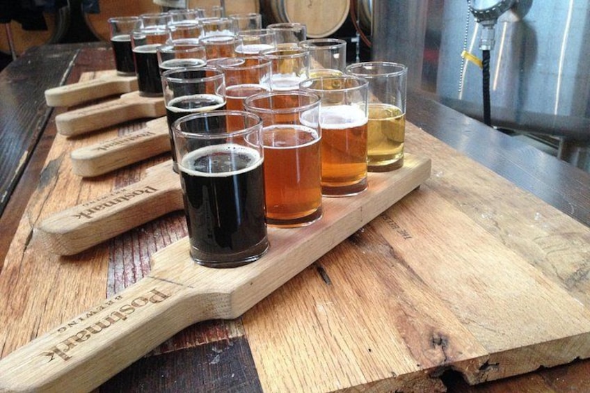 Un vassoio di legno con diversi bicchieri di birra, alcuni con schiuma. 4