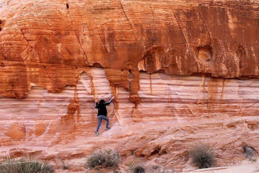 A person rock climbing on a large red rock formation. 5