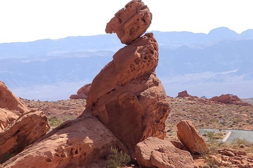 A red rock formation with a balanced rock stack in a desert landscape. 3