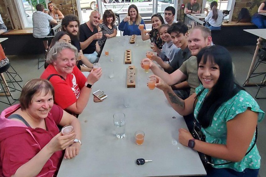 Een groep mensen zit rond een tafel met drankjes en maakt een praatje. 5