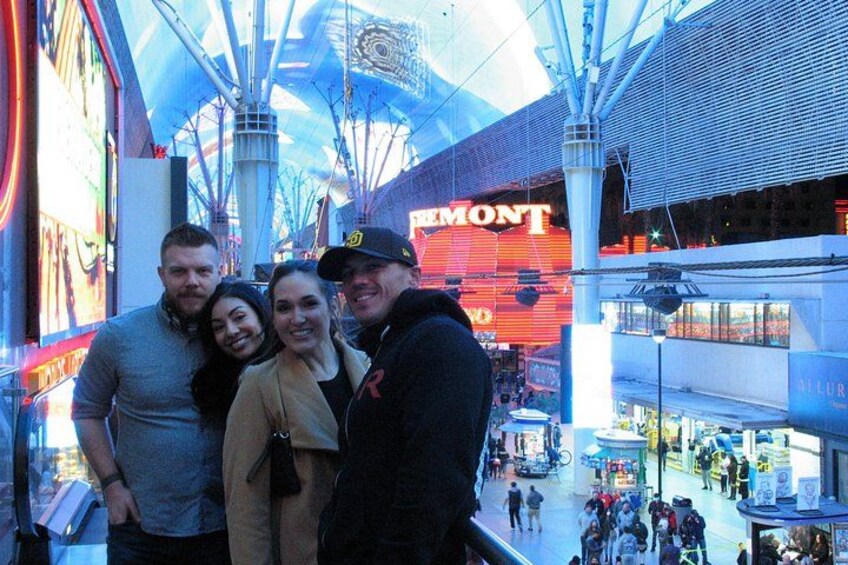 Un grupo de personas de pie en un centro comercial, con un gran letrero que dice 'REMMONT' al fondo. 2