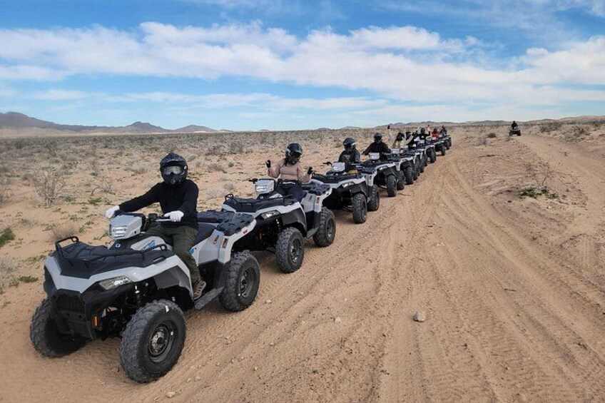 Une rangée de quads sur un chemin de terre, dans un paysage désertique. 1