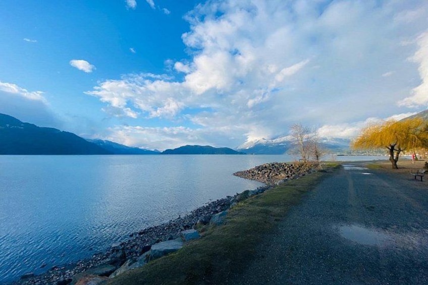 Un lac aux rives rocheuses, un sentier pavé et un arbre aux feuilles jaunes. 4