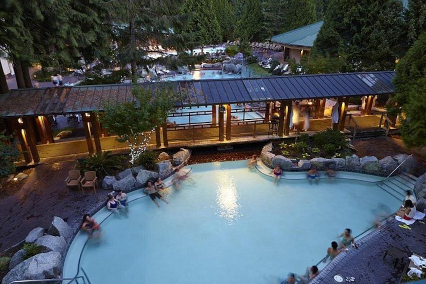 Une piscine où l’on voit des personnes, entourée de rochers et d’arbres. 1