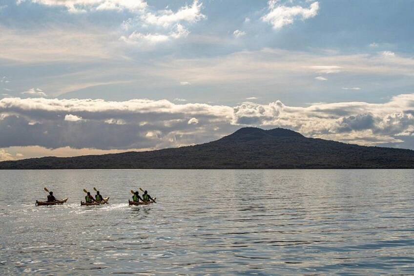 Three kayaks on calm water with a mountain in the background. 2
