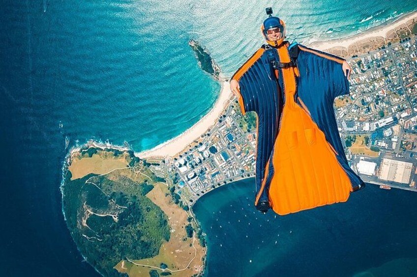 Une vue aérienne d’une zone côtière avec une plage, une petite île et une personne en parachute. 2