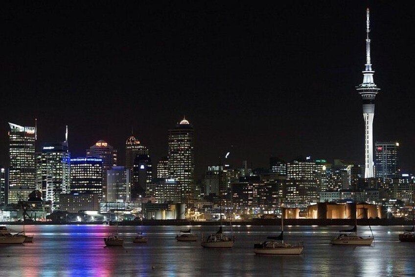 A city skyline at night with illuminated buildings and a prominent tower. 3