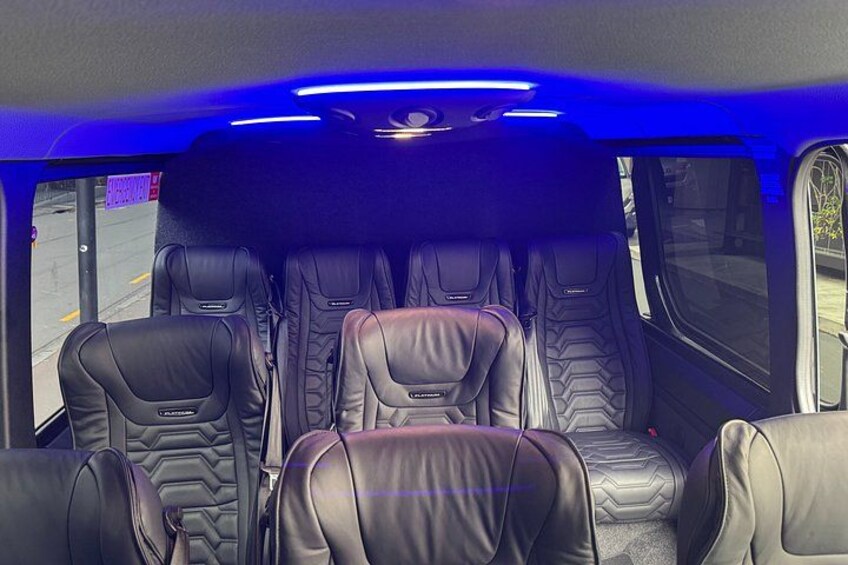 A vehicle interior with leather seats and blue lighting. 2