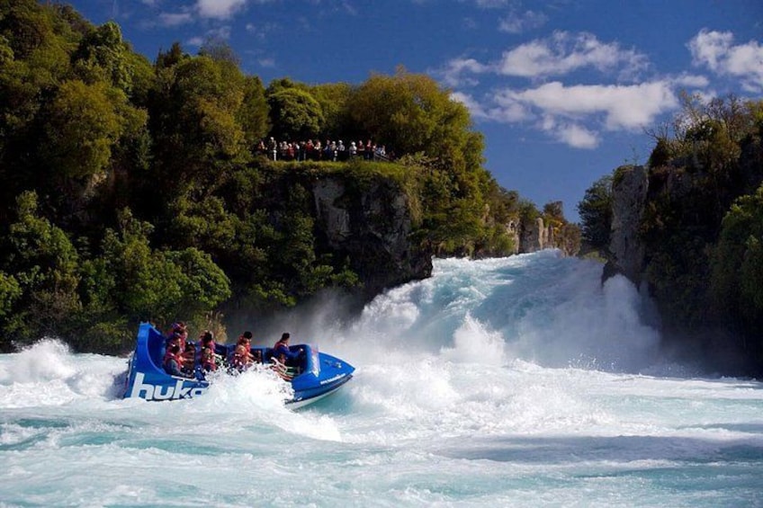 A blue raft navigating a turbulent river surrounded by cliffs and dense greenery. 1