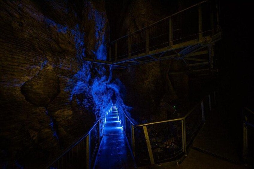 A dimly lit tunnel with a blue light leading to a staircase. 2
