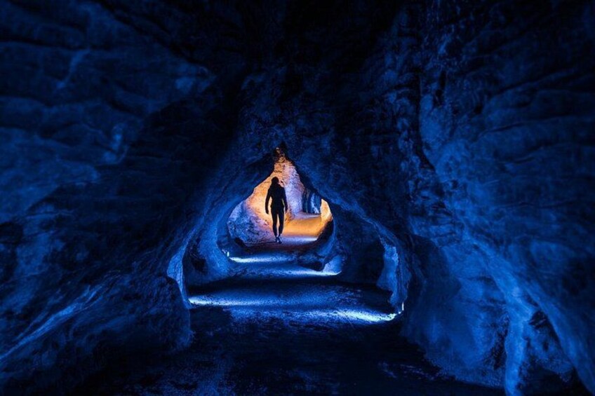 A person walking through a cave illuminated by a light source. 3