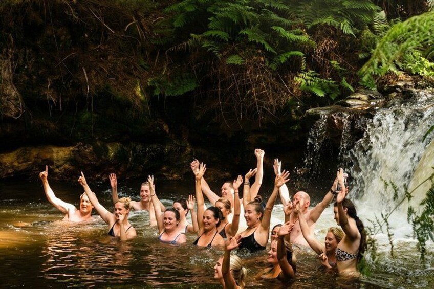 A group of people in a natural setting with a waterfall and dense greenery. 3