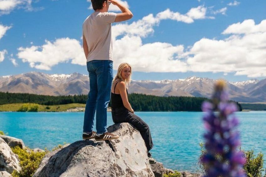 A couple by a lake with mountains in the background. 2