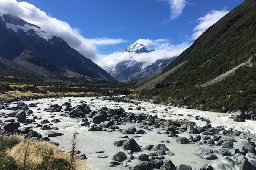 Un río con rocas, montañas y picos nevados bajo un cielo despejado. 3