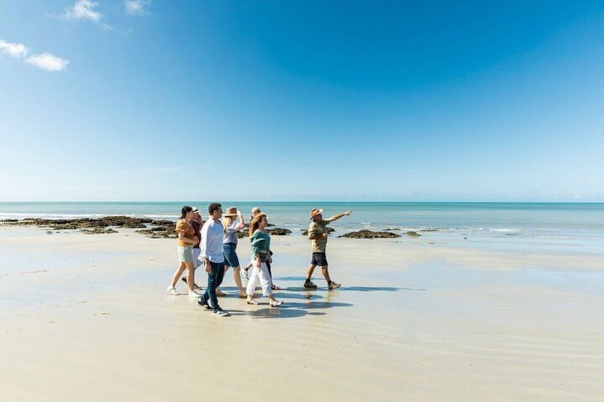 Un groupe de personnes se trouve sur une plage de sable, avec l’océan en arrière-plan. 2