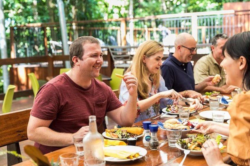 A group of people dining at an outdoor restaurant with various dishes and drinks on the table. 2