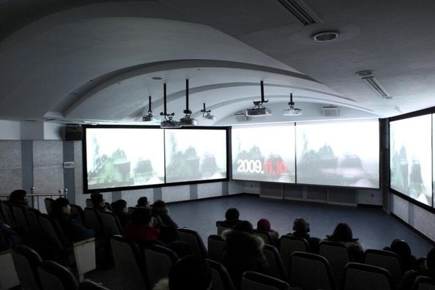 A conference room with a large screen displaying a presentation. 3