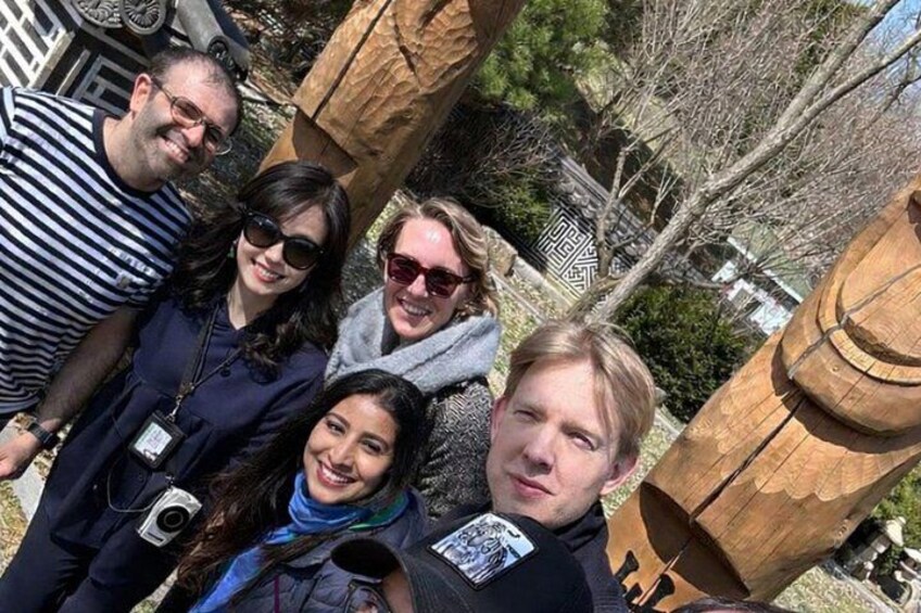 A group of people posing in front of a wooden structure with carved details. 4