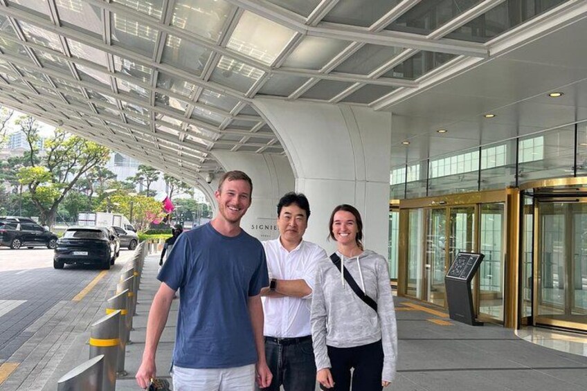 Three people standing in front of a modern building with a glass entrance. 2
