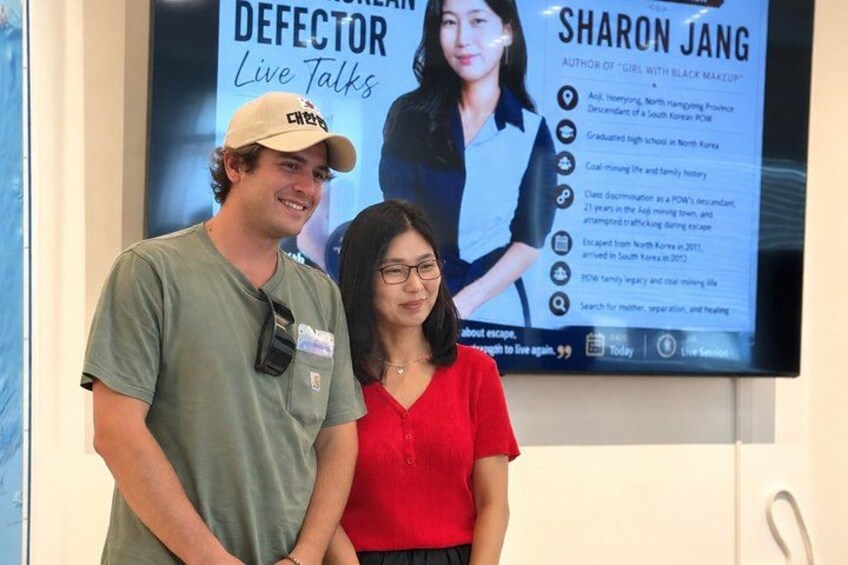 En mand og en kvinde står foran et skærmbillede, der viser et oplæg om Sharon Jang. 1