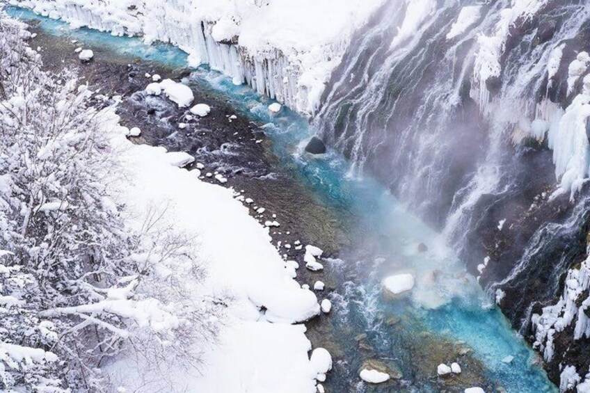 A snowy waterfall with ice formations and a river. 5