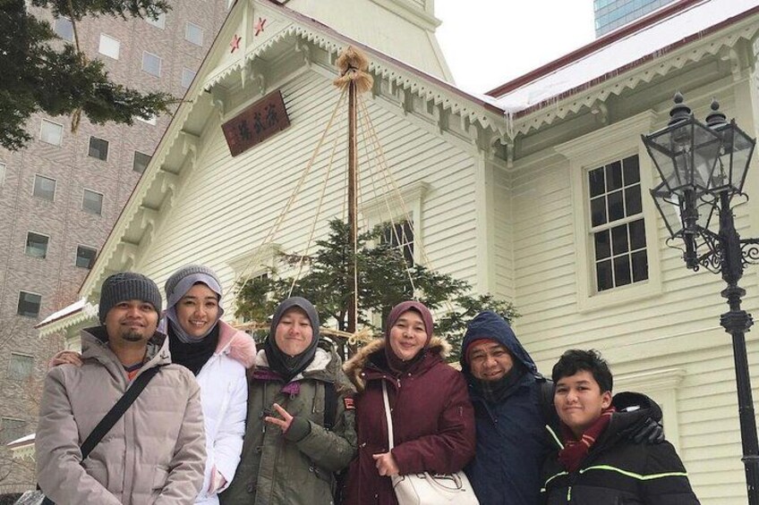 Un groupe de personnes posant devant un bâtiment à l’architecture traditionnelle, caractérisé par une enseigne bien visible et un lampadaire. 2