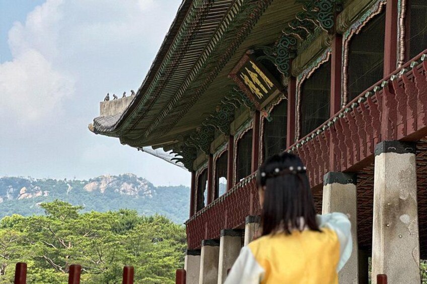 A traditional building with ornate architecture, a balcony, and a mountainous landscape in the background. 3
