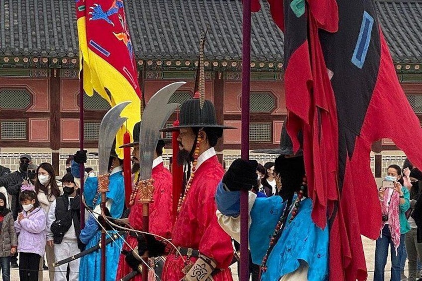 A historical reenactment with individuals in traditional costumes, a crowd of spectators, and a traditional building in the background. 2