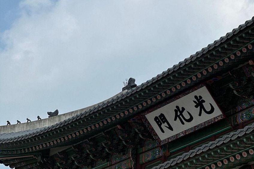 A traditional Korean roof with intricate designs and a sign with Korean characters. 4