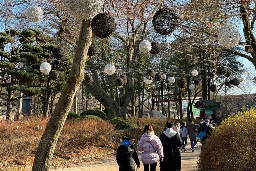 A pathway lined with trees and spherical decorations, with people walking along it. 2
