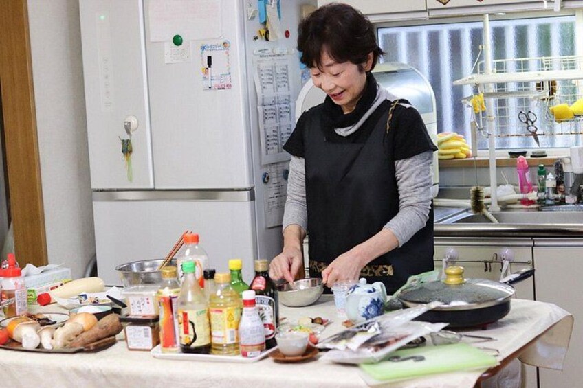 A person cooking in a kitchen with various food items and cooking utensils on the counter. 1