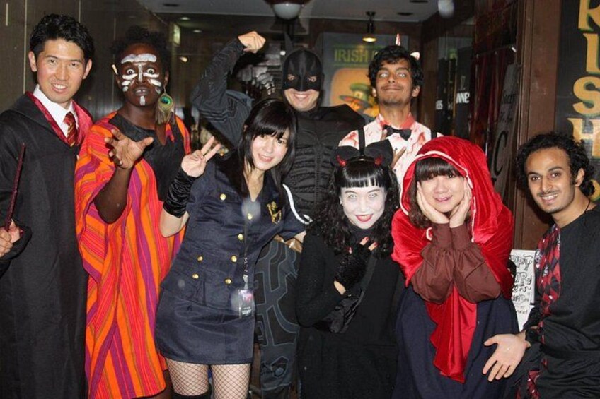 A group of people in various costumes, including a person in a red cape and another in a black outfit with a hood. 2