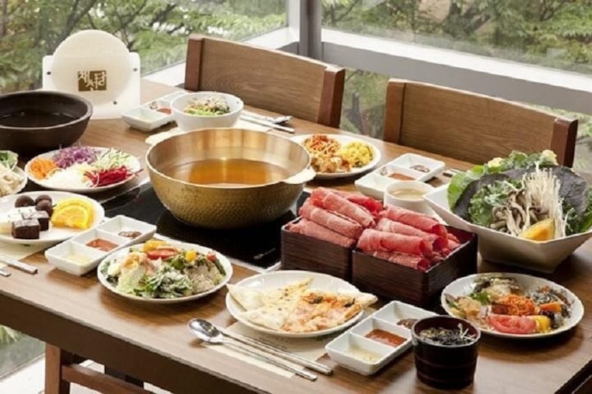 A dining table with various dishes, including bowls of soup, plates of food, and a large bowl of broth. 2