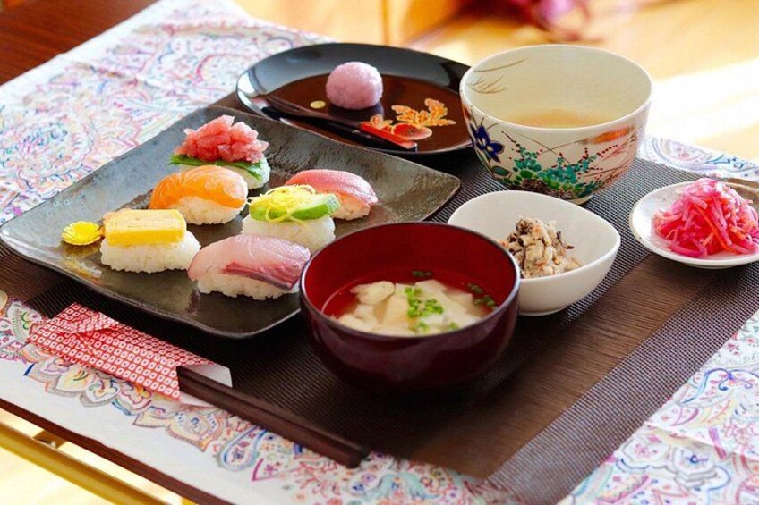Variedad de sushi en un plato, un tazón de sopa y una pequeña fuente de jengibre encurtido. 5