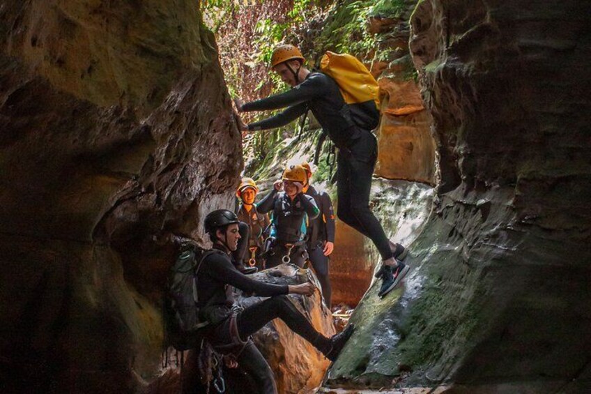 A group of people engaged in a canyon climbing activity, wearing helmets and harnesses. 5