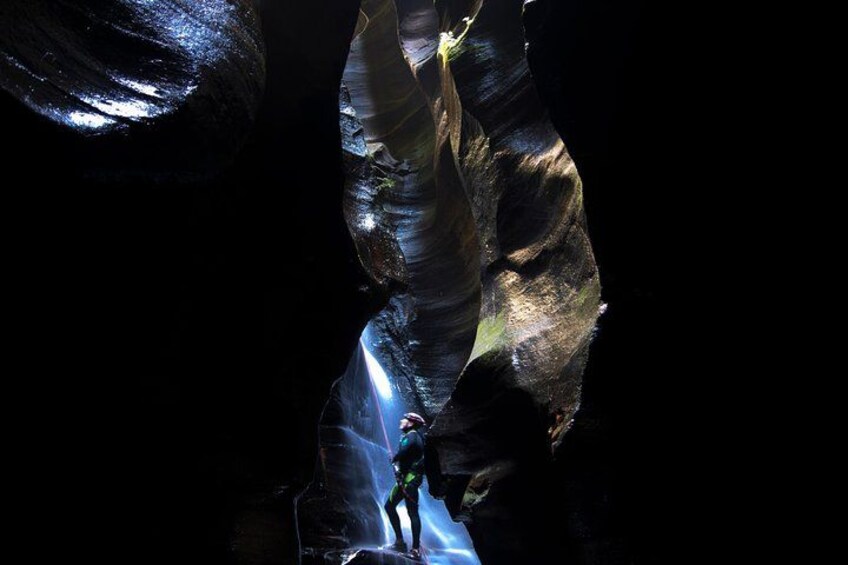 A person climbing a narrow, rocky canyon wall. 2