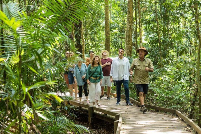 A group of people walking on a wooden bridge in a forest. 1