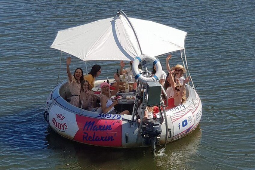 A boat with people on board, a canopy, and a logo. 1