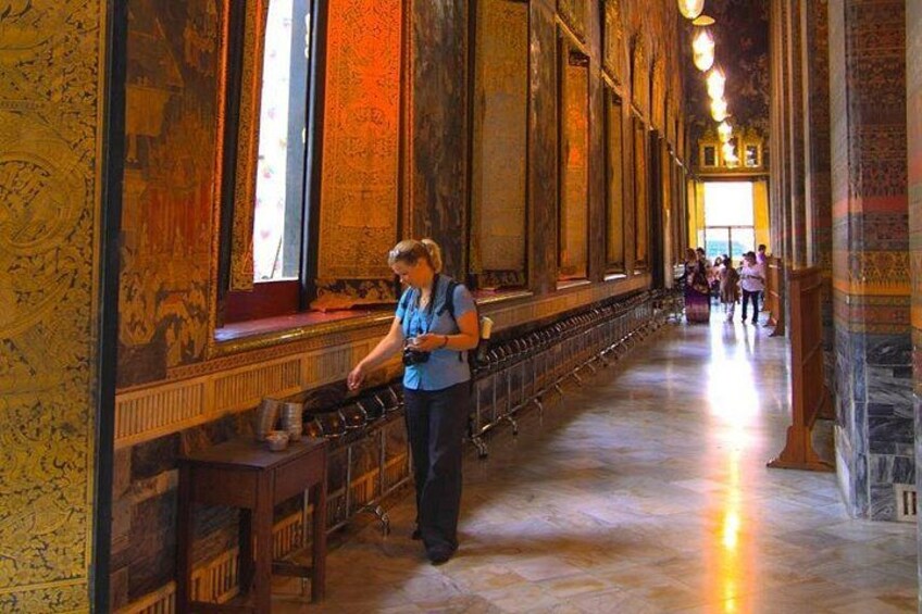 A person standing in a long corridor with ornate walls and a high ceiling. 4