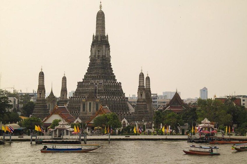 A large temple with a tall spire, surrounded by smaller buildings and boats on the water. 2