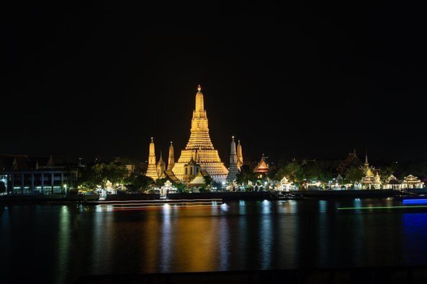 A night view of a temple complex with illuminated structures reflecting on the water. 4