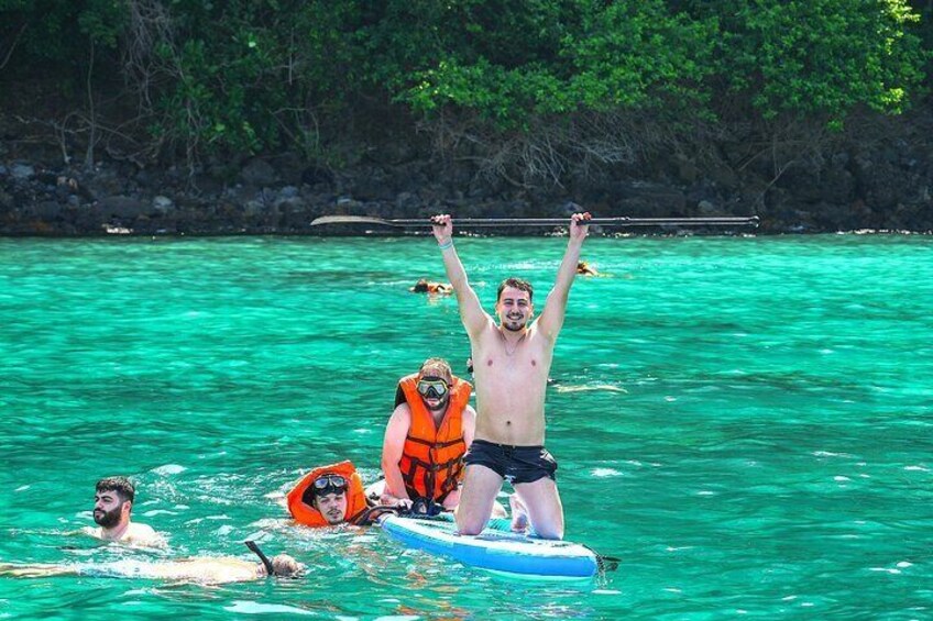 People in a turquoise body of water, some on a blue raft, others swimming. 5