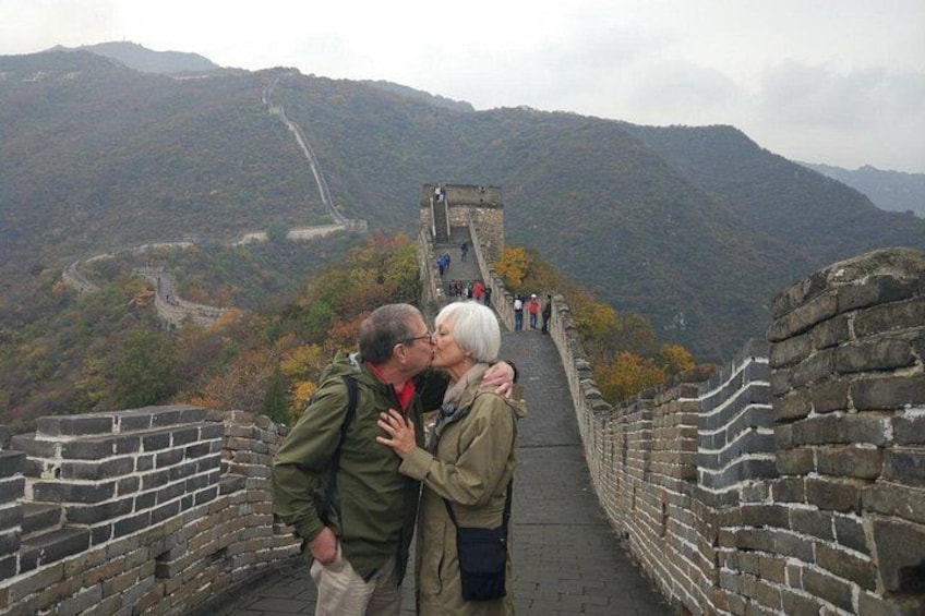 Un couple s’embrasse sur la Grande Muraille de Chine, avec des montagnes en arrière-plan. 2
