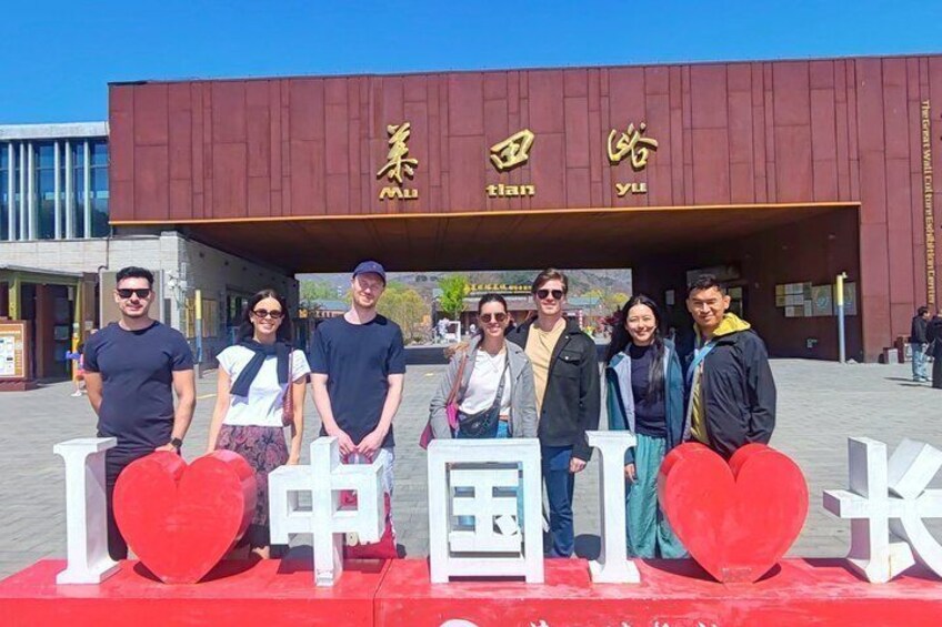 Eine Gruppe von Personen posiert vor einem Gebäude mit chinesischen Schriftzeichen und großen Herzen. 4