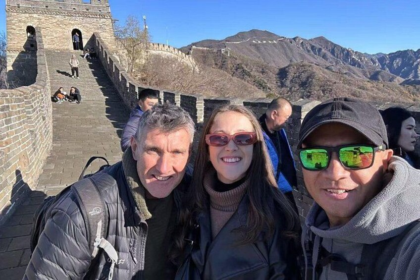 A group of people taking a selfie with the Great Wall of China in the background. 2