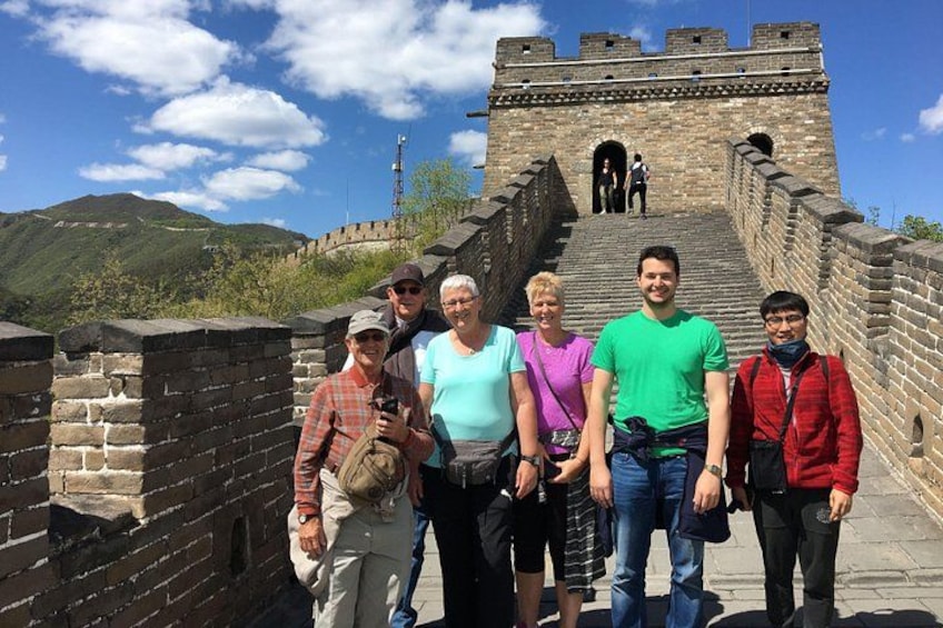 Eine Gruppe von Menschen steht auf der Chinesischen Mauer, mit der Mauer und Bergen im Hintergrund. 2