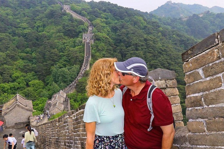 Een stel dat elkaar kust op de Chinese Muur, met weelderige begroeiing op de achtergrond. 2