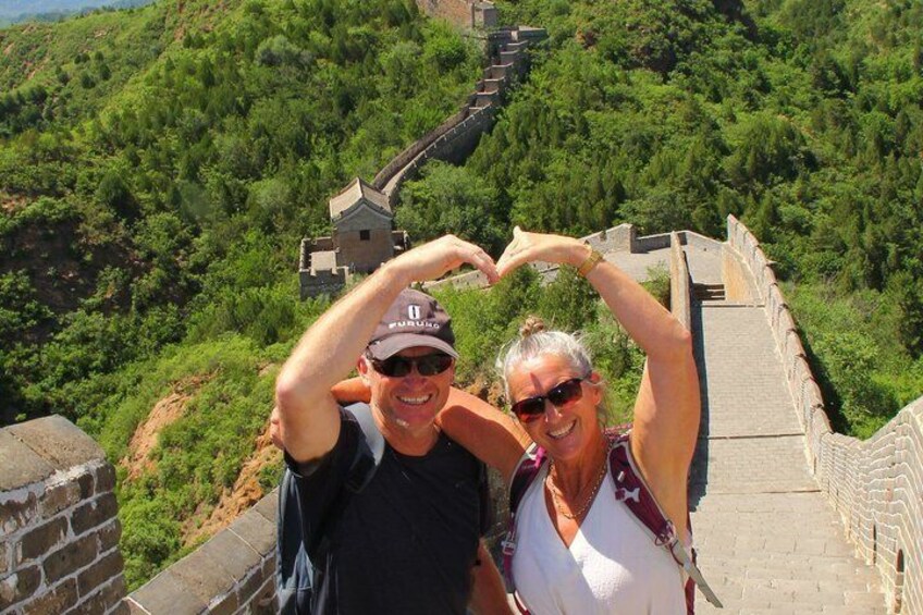 A couple making a heart shape with their hands on the Great Wall of China. 1